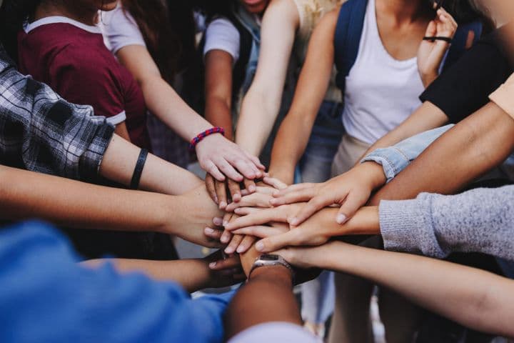 Diverse hands stacked together in a circle, symbolizing unity, collaboration, and collective team spirit.